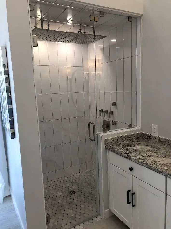 A bathroom with a walk in shower and a sink.