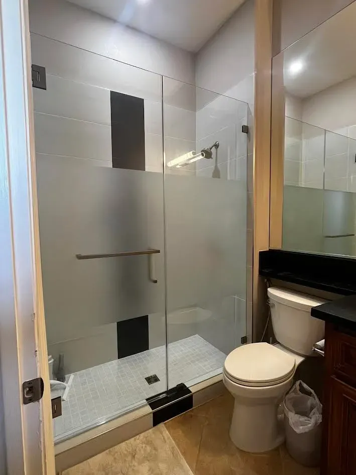 A bathroom with a toilet , shower and mirror.