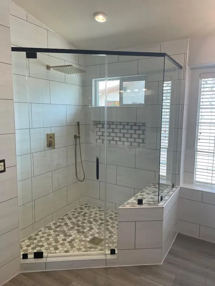 A bathroom with a walk in shower with a glass door.