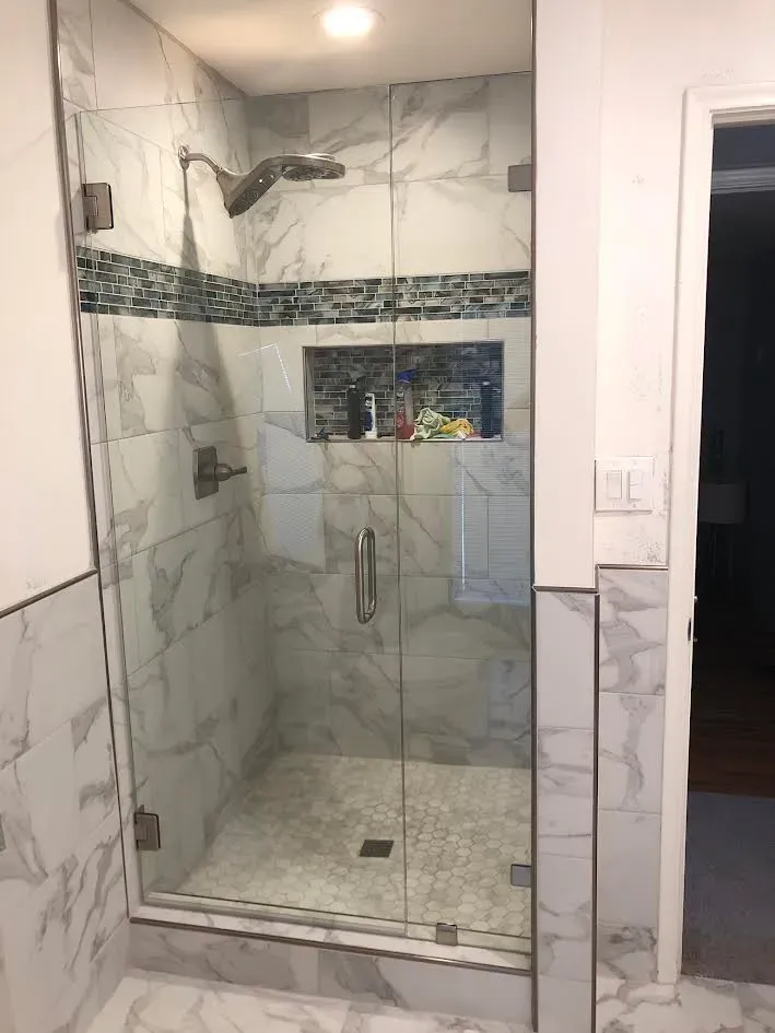 A bathroom with a walk in shower with a glass door.