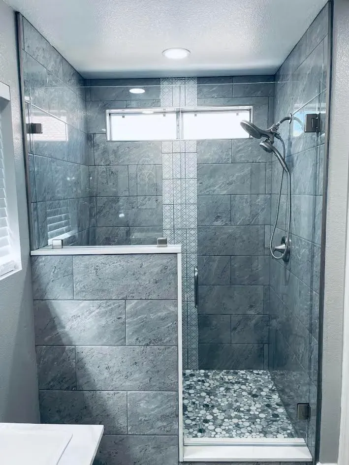A bathroom with a walk in shower with a glass door.