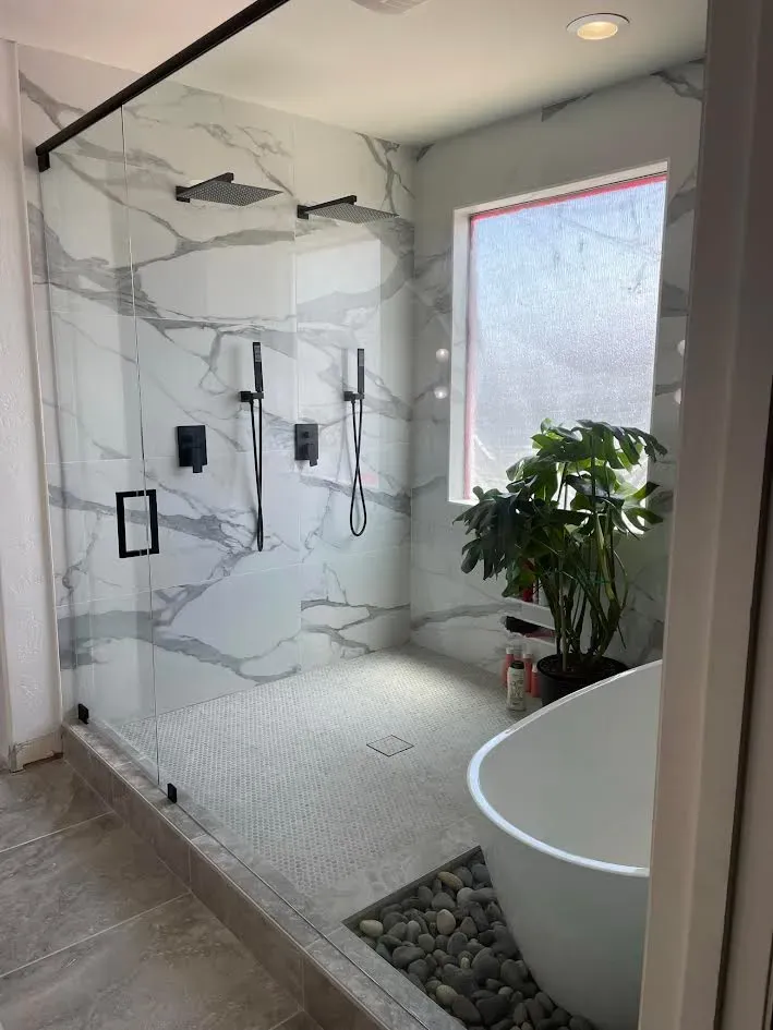 A bathroom with a walk in shower and a tub.