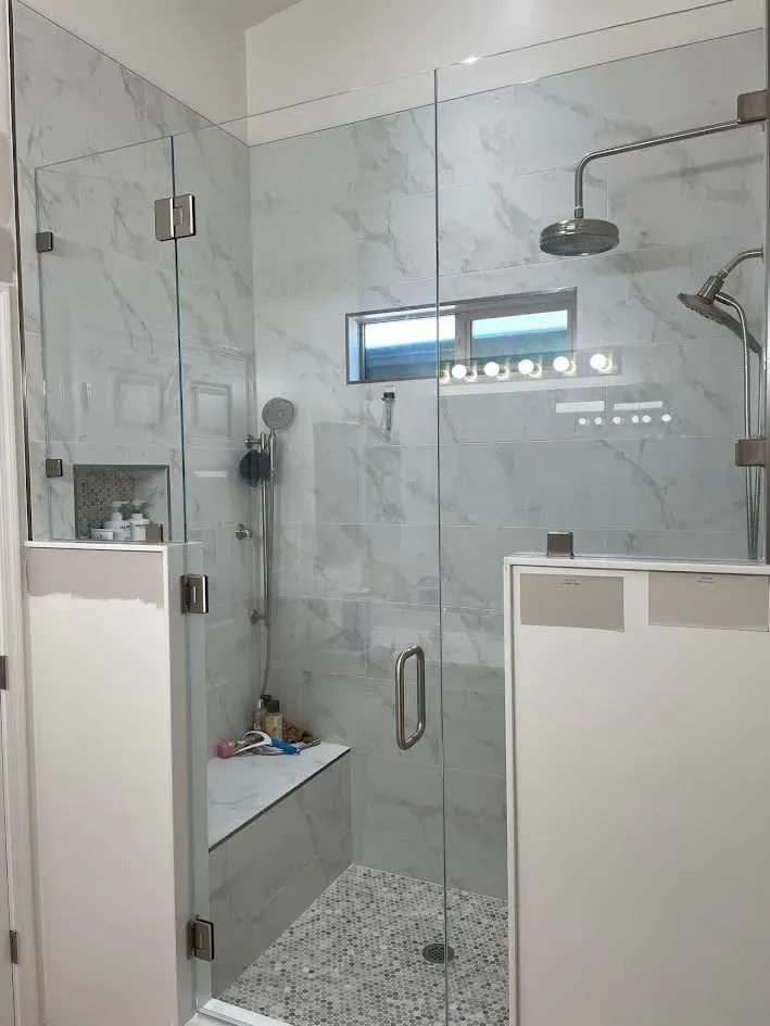 A bathroom with a walk in shower with a glass door.