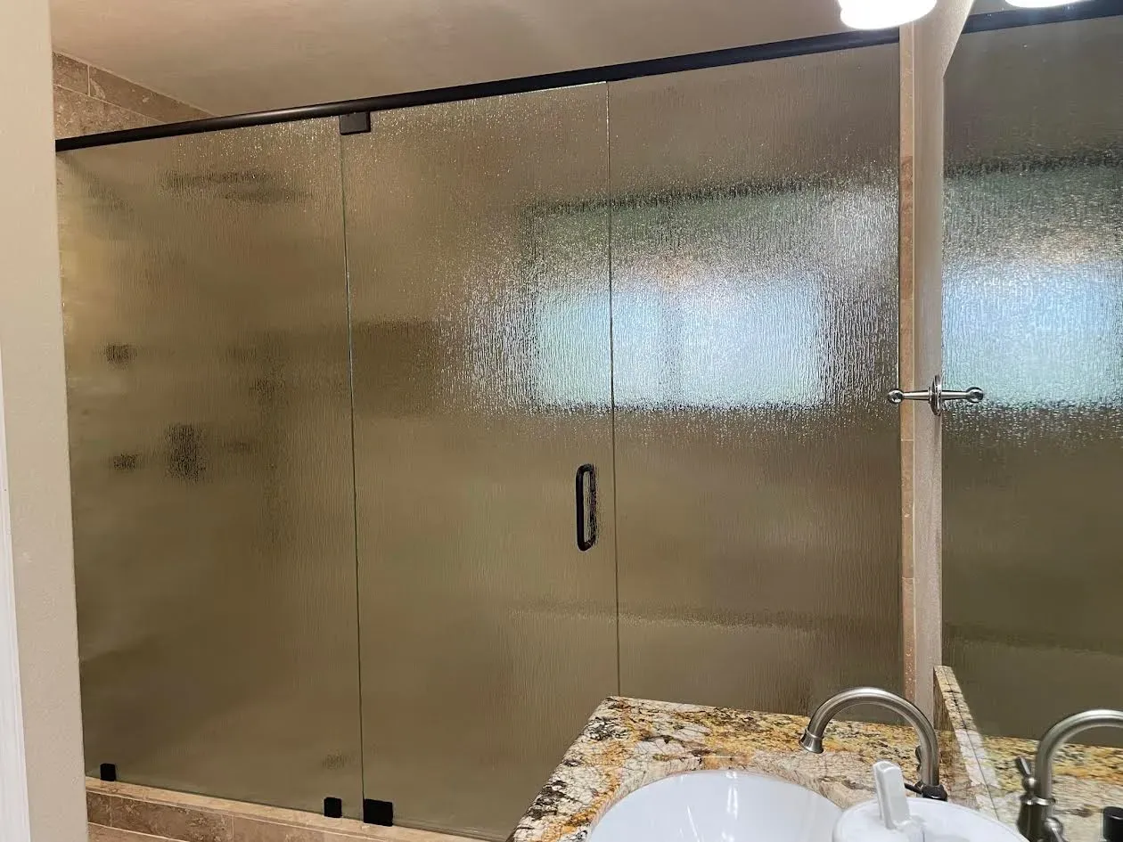 A bathroom with a walk in shower and a sink.