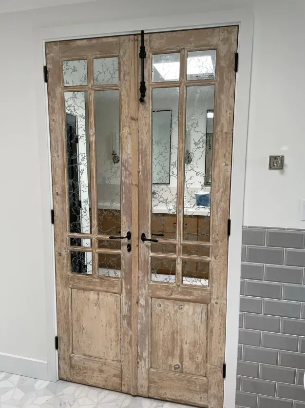 A pair of wooden doors with glass in a bathroom.