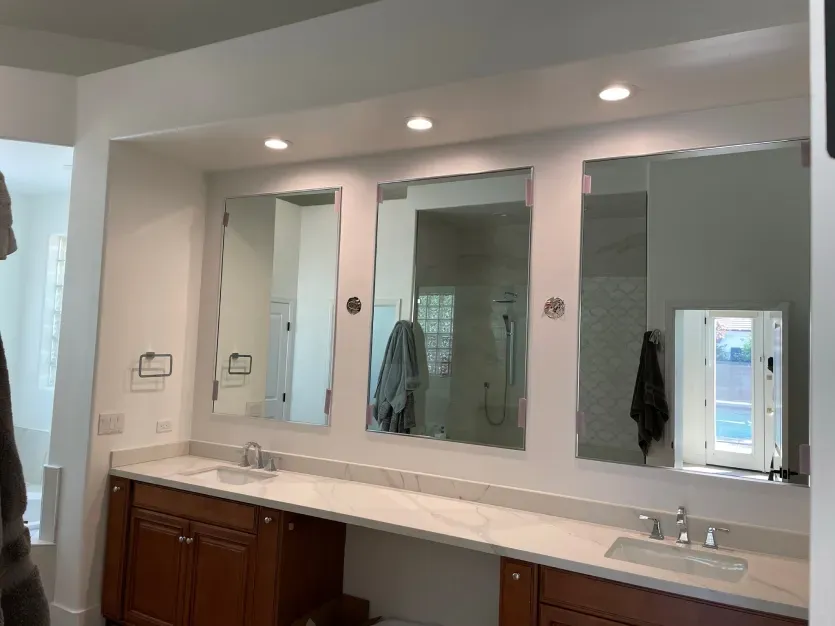 A bathroom with two sinks and three mirrors.