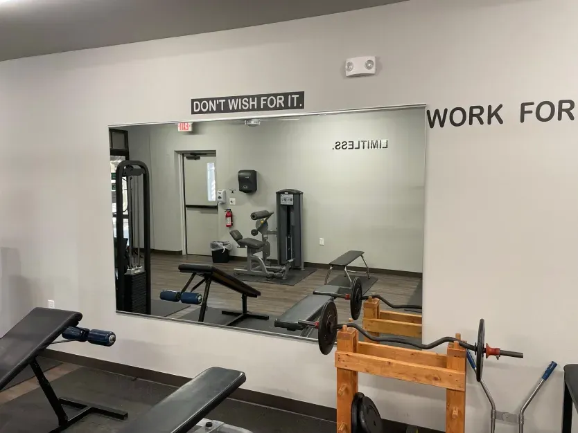 A gym with a large mirror on the wall and a sign that says `` work for it ''.