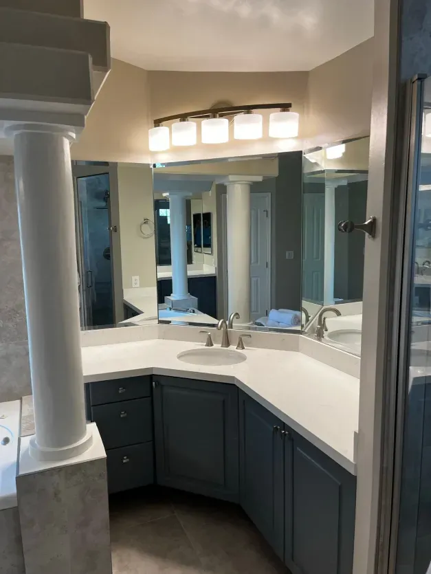 A bathroom with blue cabinets and a large mirror
