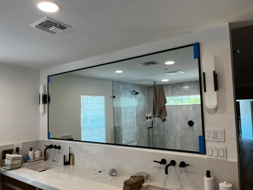 A bathroom with a large mirror and a sink.