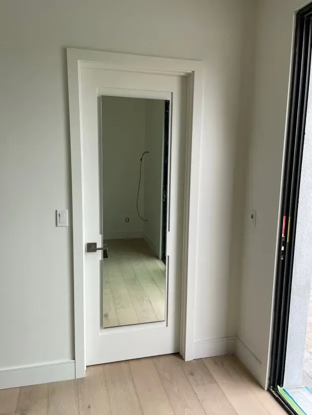 A white door with a mirror on it in a room.