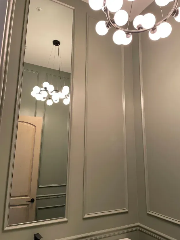 A bathroom with a large mirror and a chandelier hanging from the ceiling.