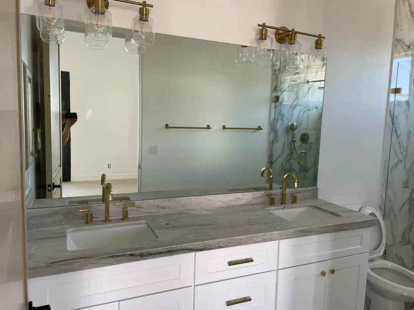 A bathroom with two sinks , a toilet and a large mirror.