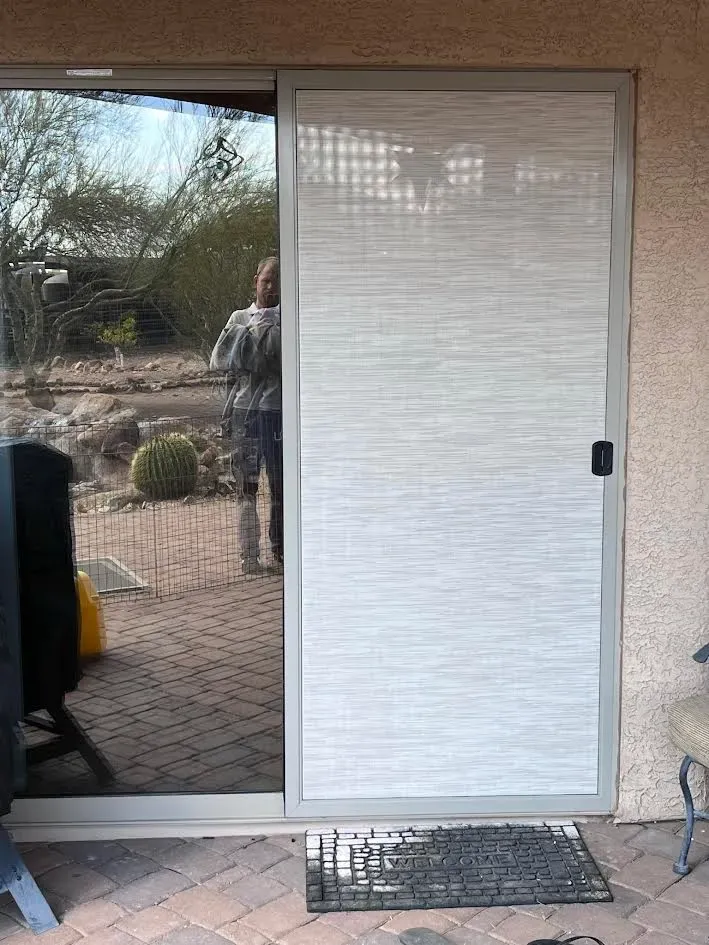 A sliding glass door with blinds on it is on a patio.