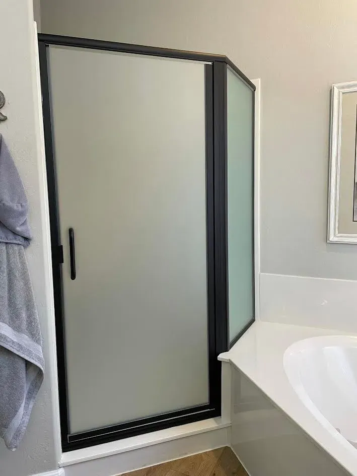 A bathroom with a shower door and a bathtub.