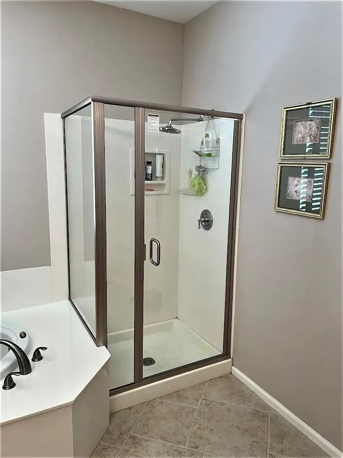 A bathroom with a walk in shower and a tub.
