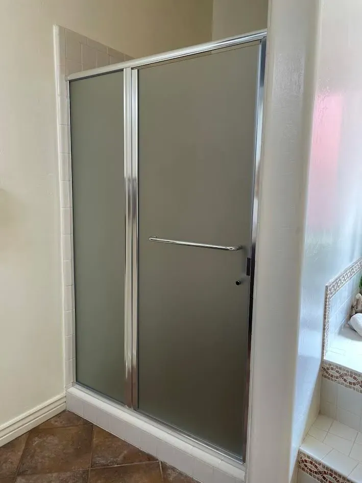 A bathroom with a sliding glass shower door.