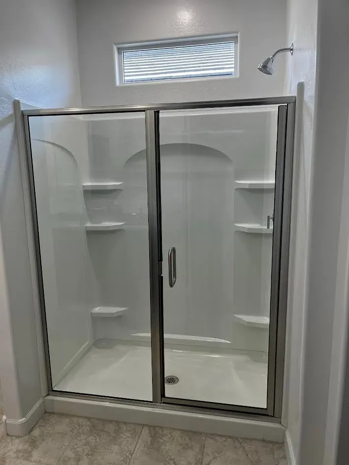 A bathroom with a walk in shower and a window.