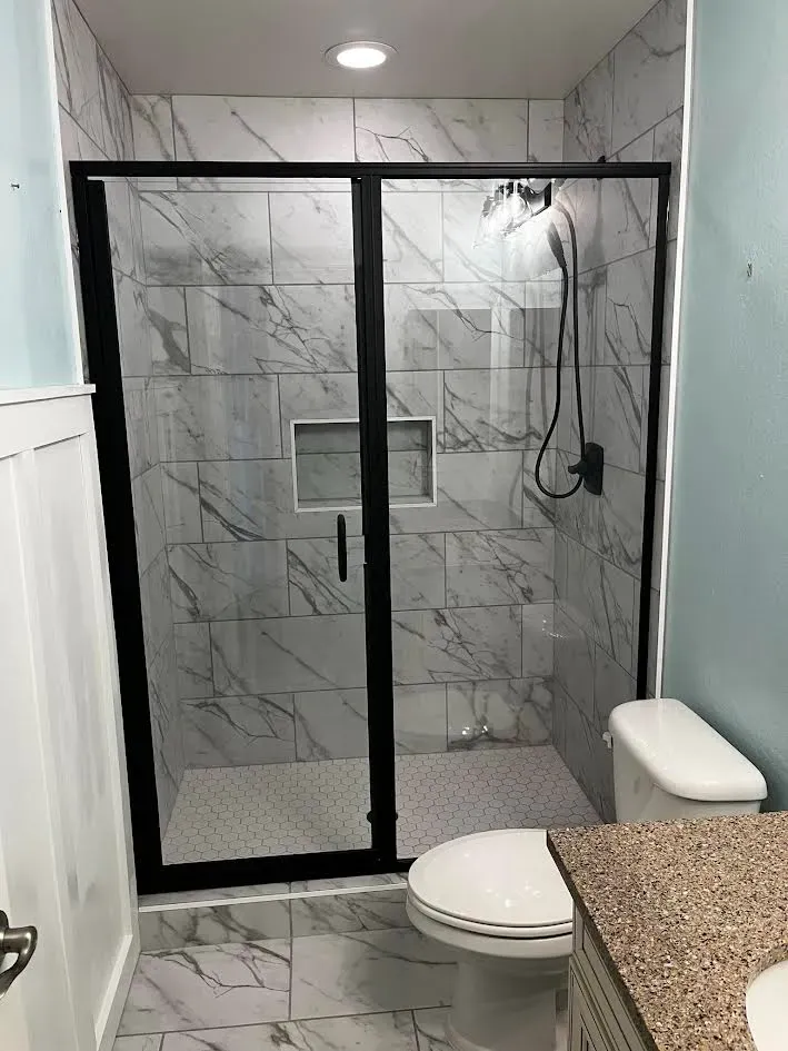A bathroom with a toilet , sink and shower stall.