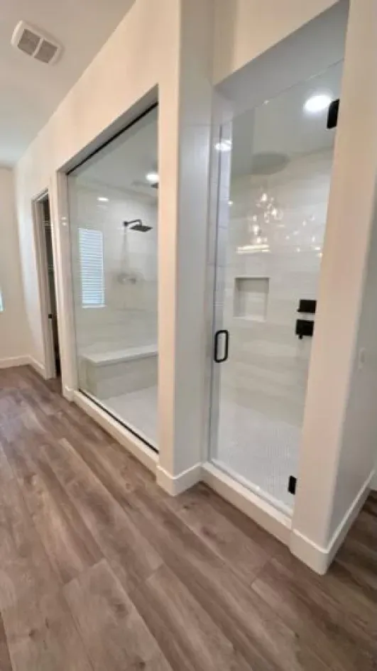 A bathroom with a walk in shower and a bench.