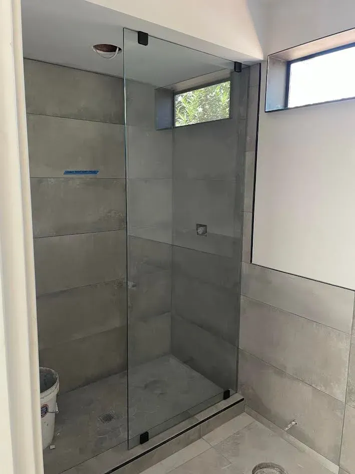 A bathroom with a walk in shower with a glass door.