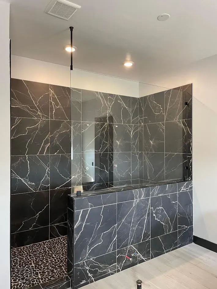A bathroom with black tiles and a walk in shower.