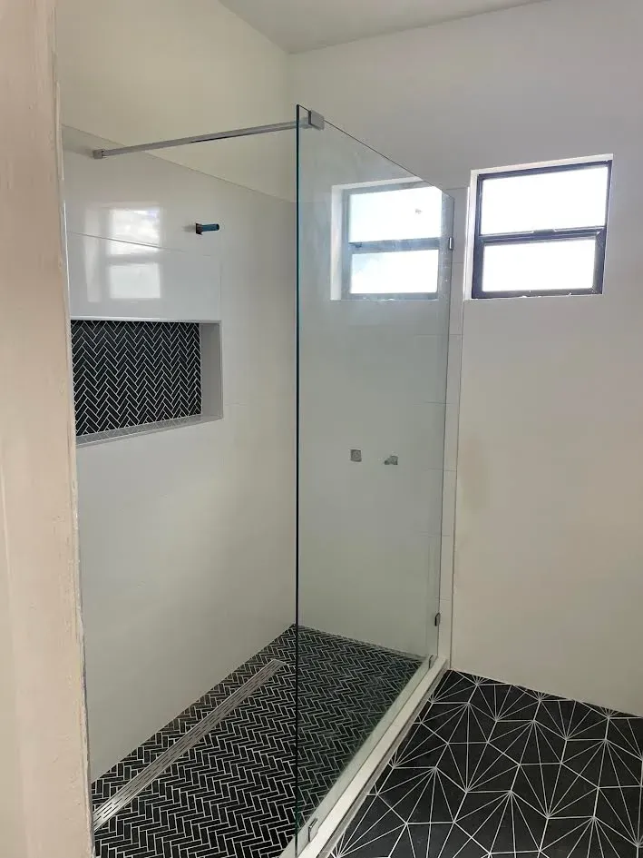 A bathroom with a walk in shower and a window.