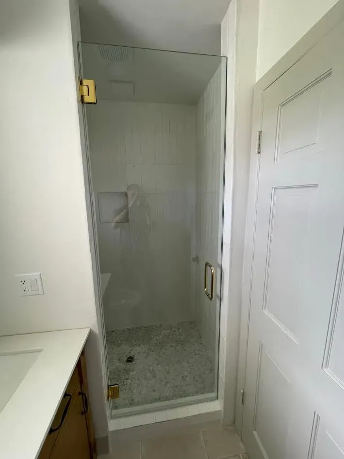 A bathroom with a walk in shower with a glass door.