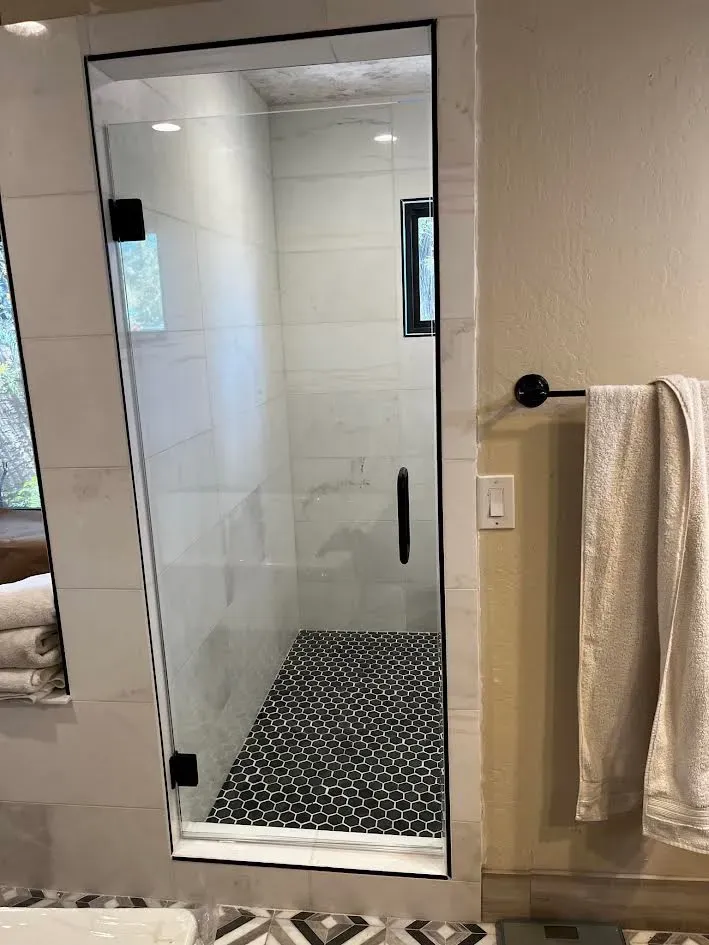 A bathroom with a walk in shower and a towel rack.