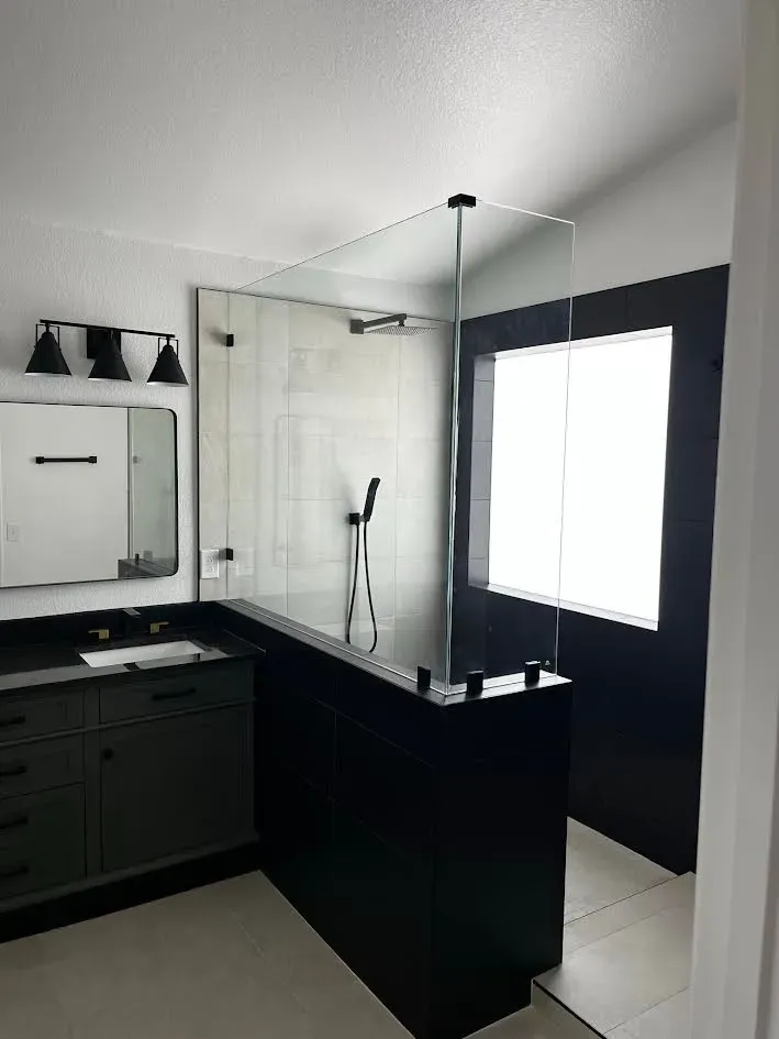 A bathroom with a walk in shower , sink , mirror and window.
