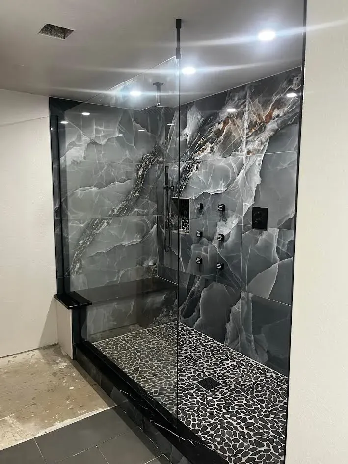 A bathroom with a walk in shower and a marble wall.