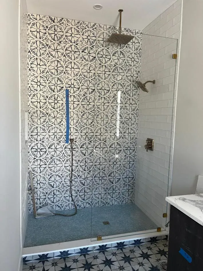 A bathroom with a walk in shower with a tiled wall.