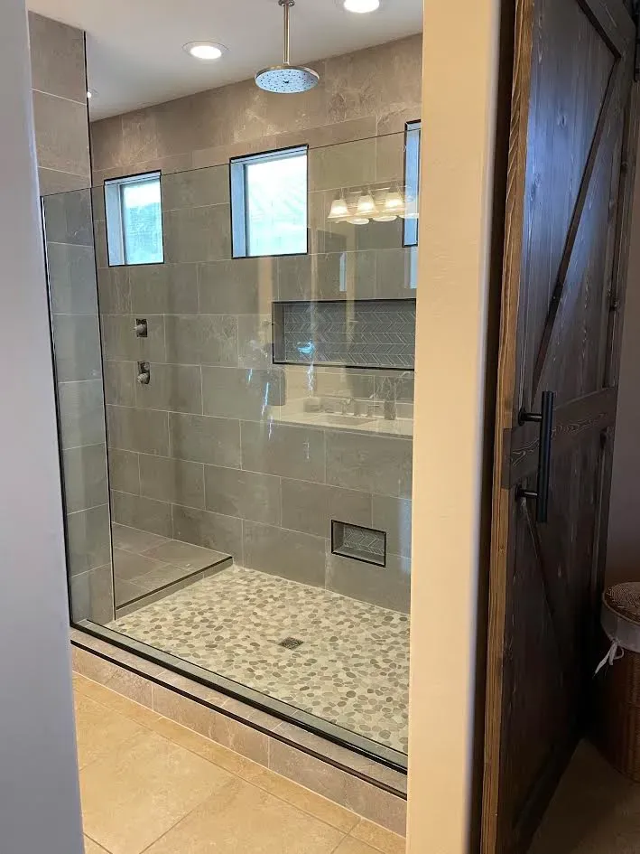 A bathroom with a walk in shower and a sink.