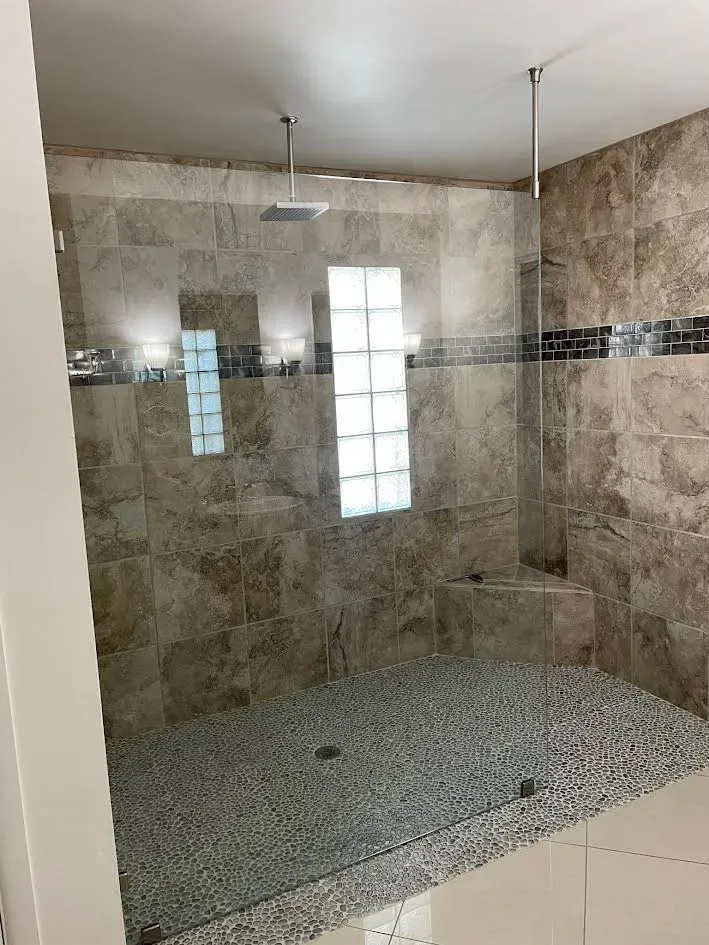 A bathroom with a walk in shower with a glass door.