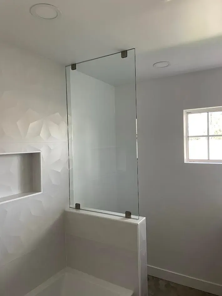 A bathroom with a glass shower door and a window.