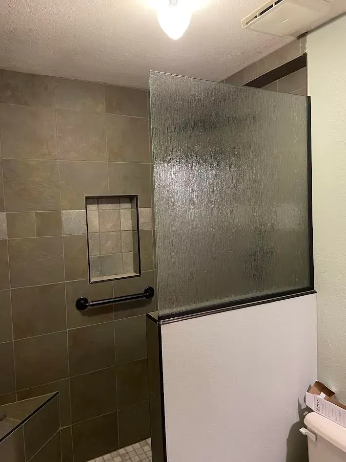 A bathroom with a glass shower door and a toilet.