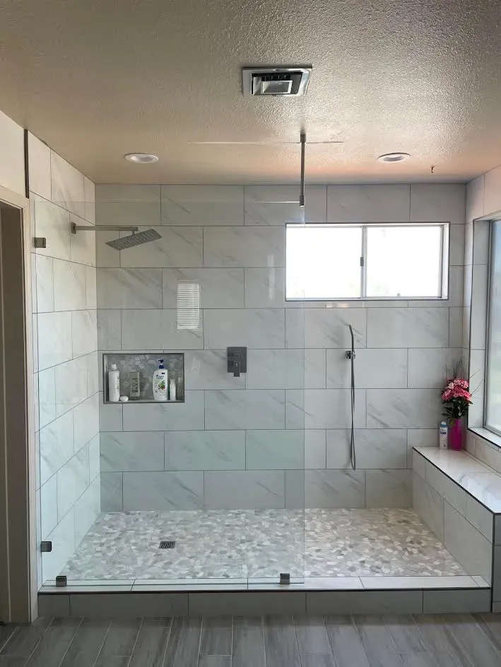 A bathroom with a walk in shower and a window.
