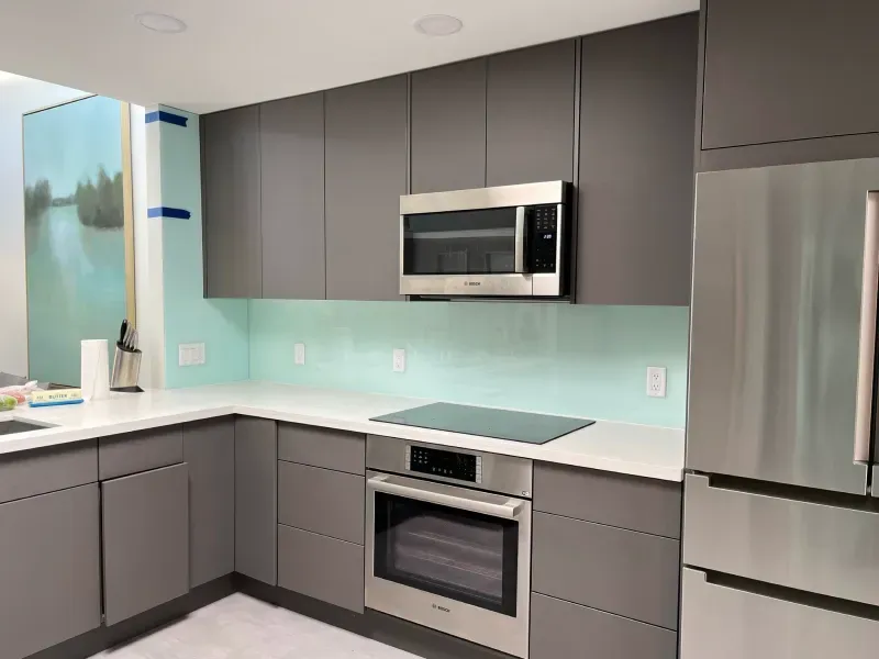 A kitchen with stainless steel appliances and gray cabinets.