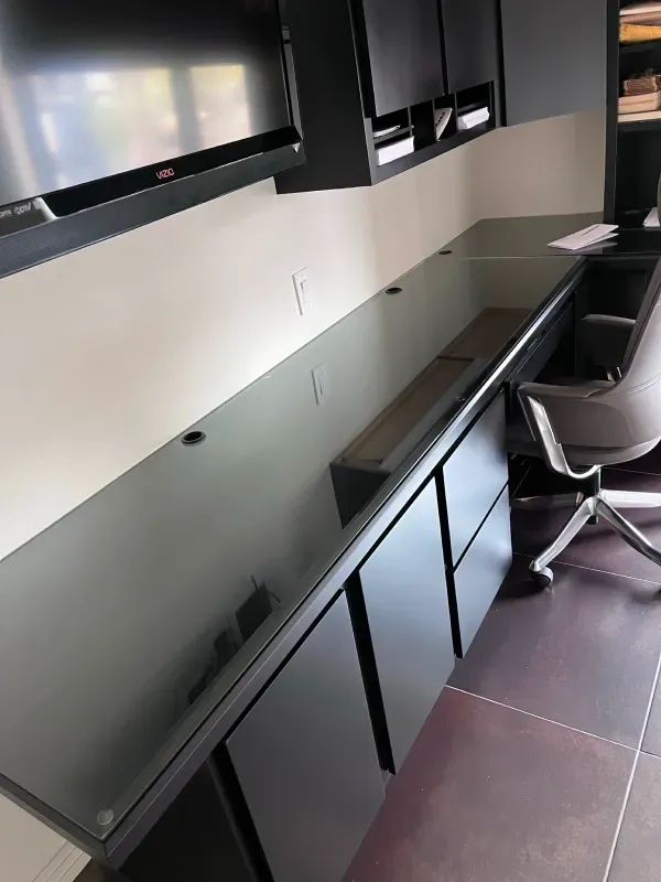 A desk with a chair and a television on the wall.