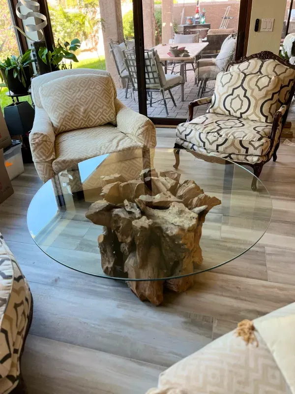 A living room with a glass coffee table and chairs.