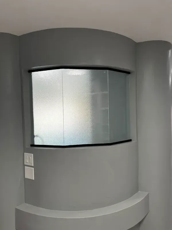 A curved window in a room with gray walls