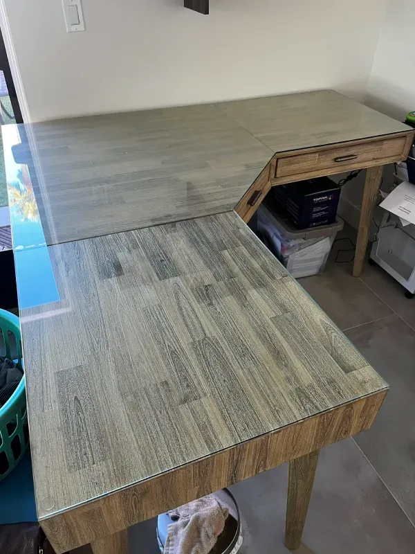 A wooden desk with a glass top in a room.