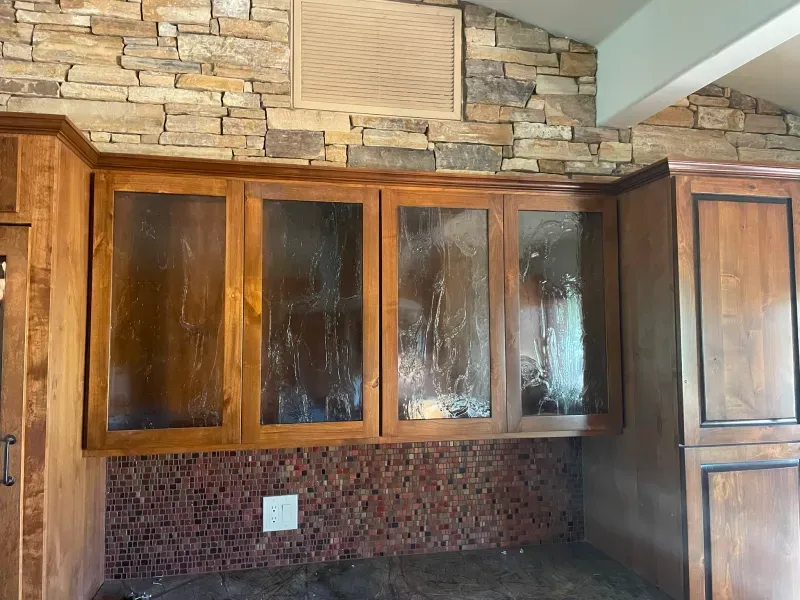 A kitchen with wooden cabinets and a stone wall