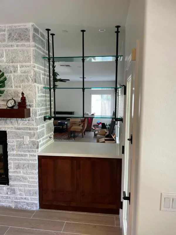 A living room with a fireplace and a shelf between the living room and the kitchen.