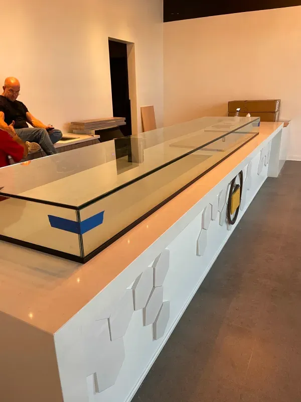 A man sits on a couch in front of a long glass counter