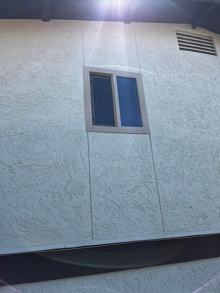 A window on the side of a building with the sun shining through it.