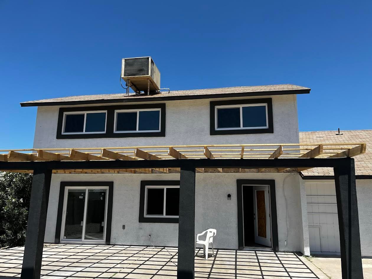 A white house with a pergola and a white chair in front of it