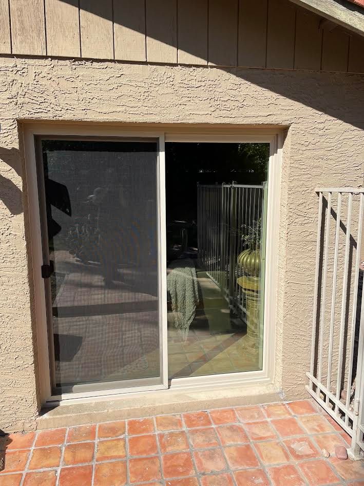 A patio with a sliding glass door and a screen door.