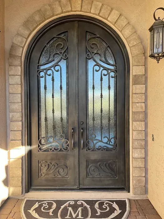 The front door of a house with a wrought iron door and a welcome mat.