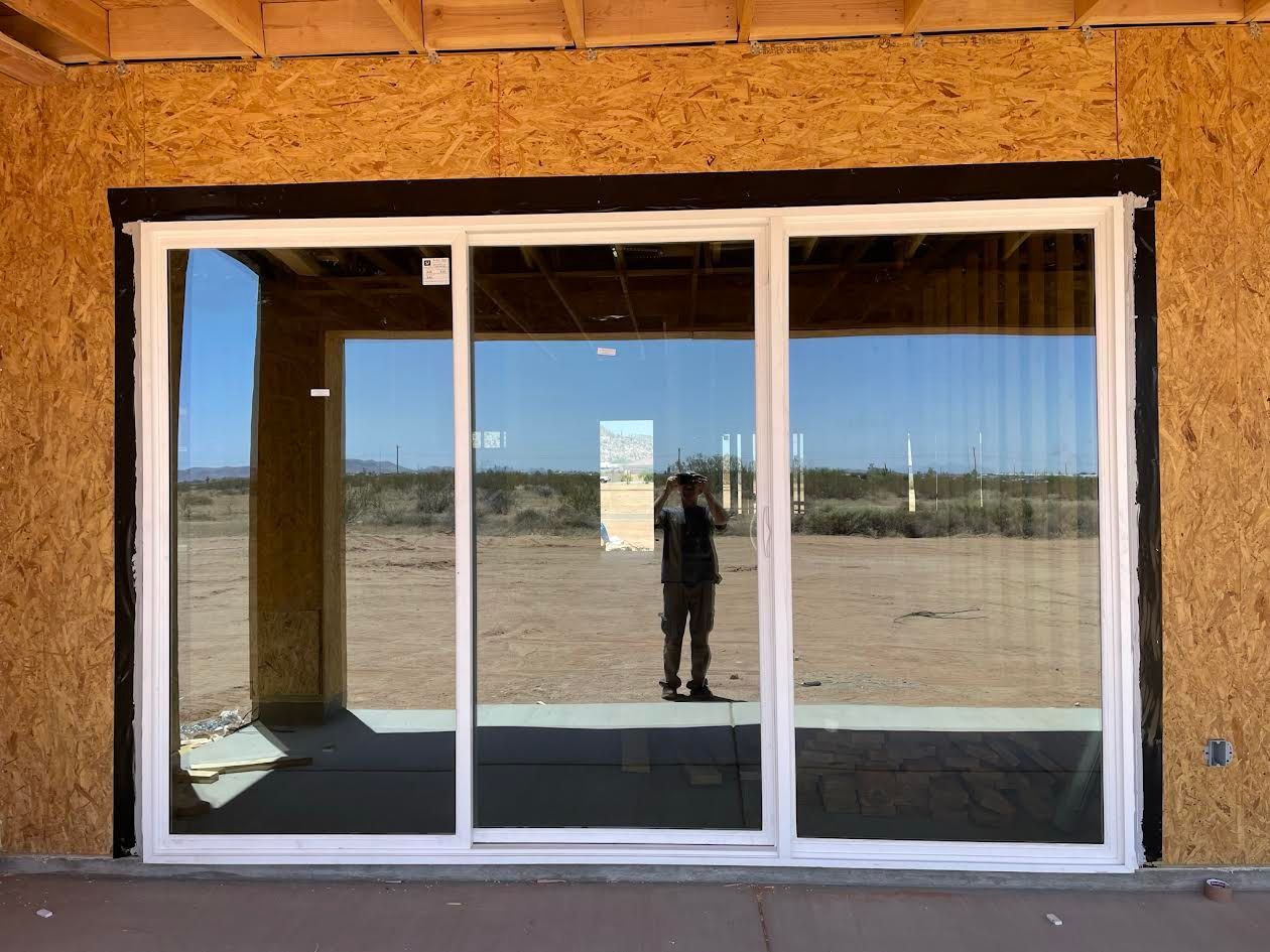 A man is standing in front of a large sliding glass door.