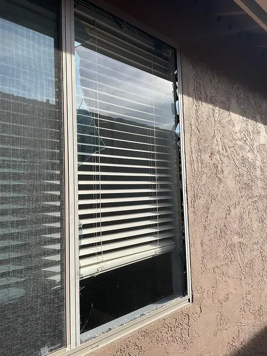 A window with blinds on it is broken in half.
